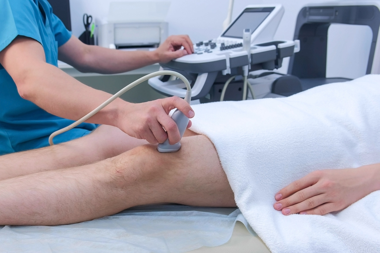 Doctor makes ultrasound of knee joint for man using ultrasound scanner, closeup.